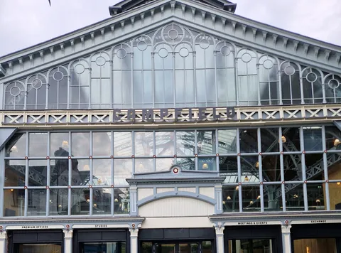 Victorian iron-and-glass gable above dark aluminium shopfront bays on a restored commercial exchange building