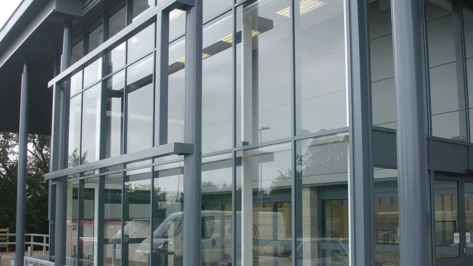 Grey aluminium curtain walling on a commercial building, seen from outside in flat daylight