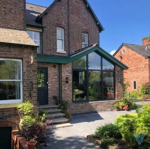 Anthracite glazed gable screen on a brick garden room with green fascia, on a Victorian house