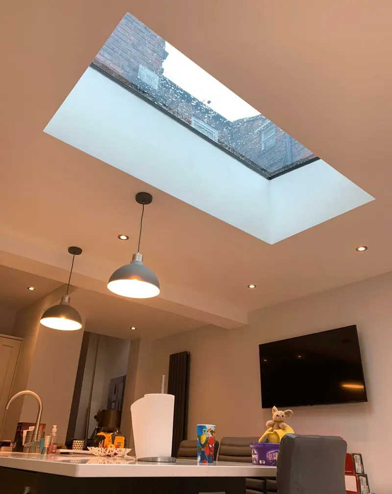 Flat rooflight seen from inside a kitchen-diner, framing sky and a neighbouring brick wall above a breakfast bar
