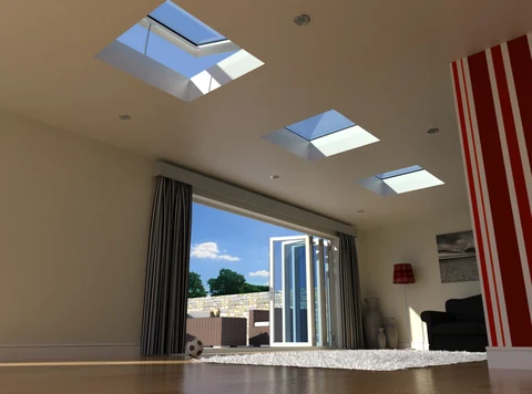Interior below three flat rooflights, nearest one open, with white bifold doors folded back to a walled terrace